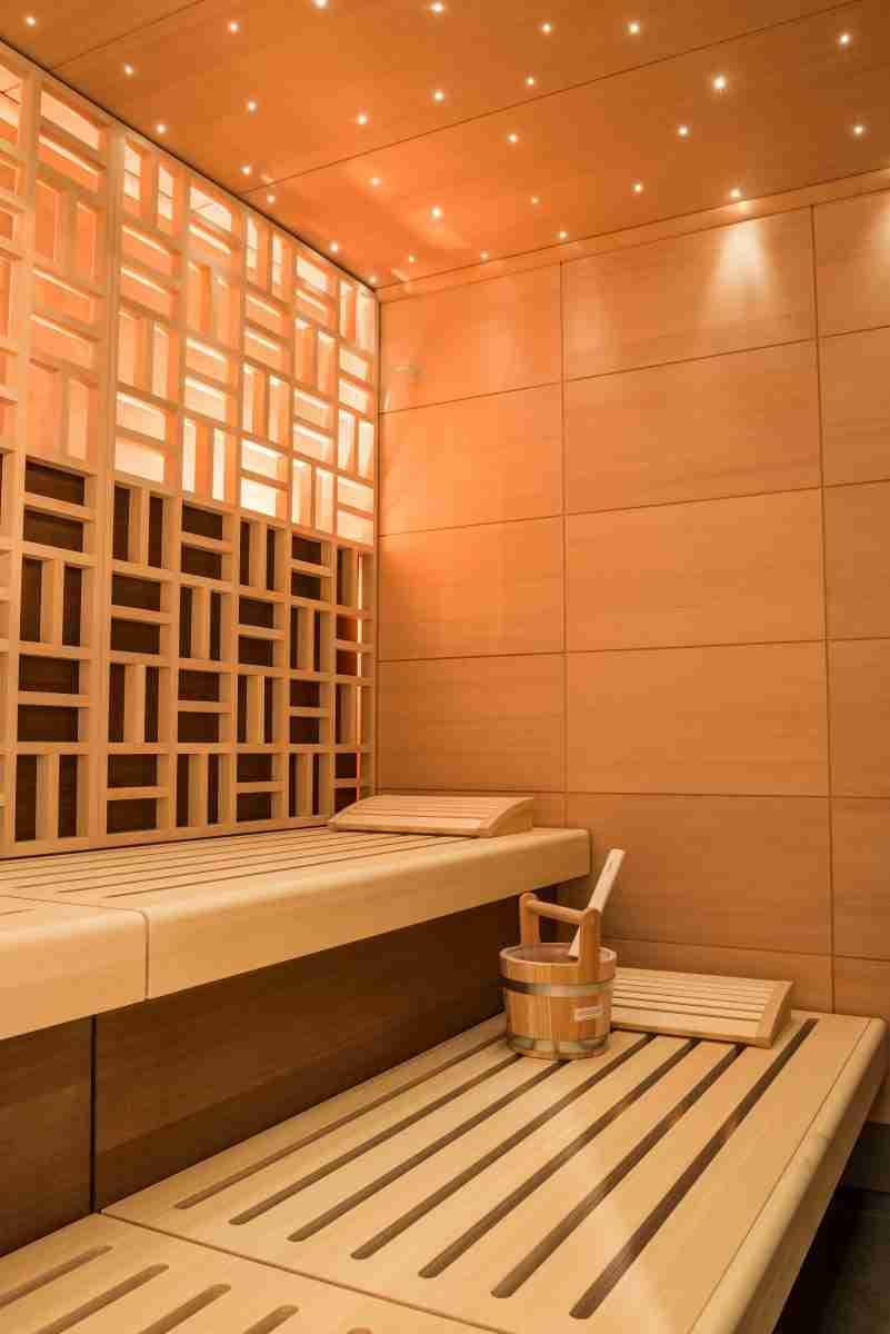 A vertical shot of a beautiful sauna room design with wall tiles and wooden bench